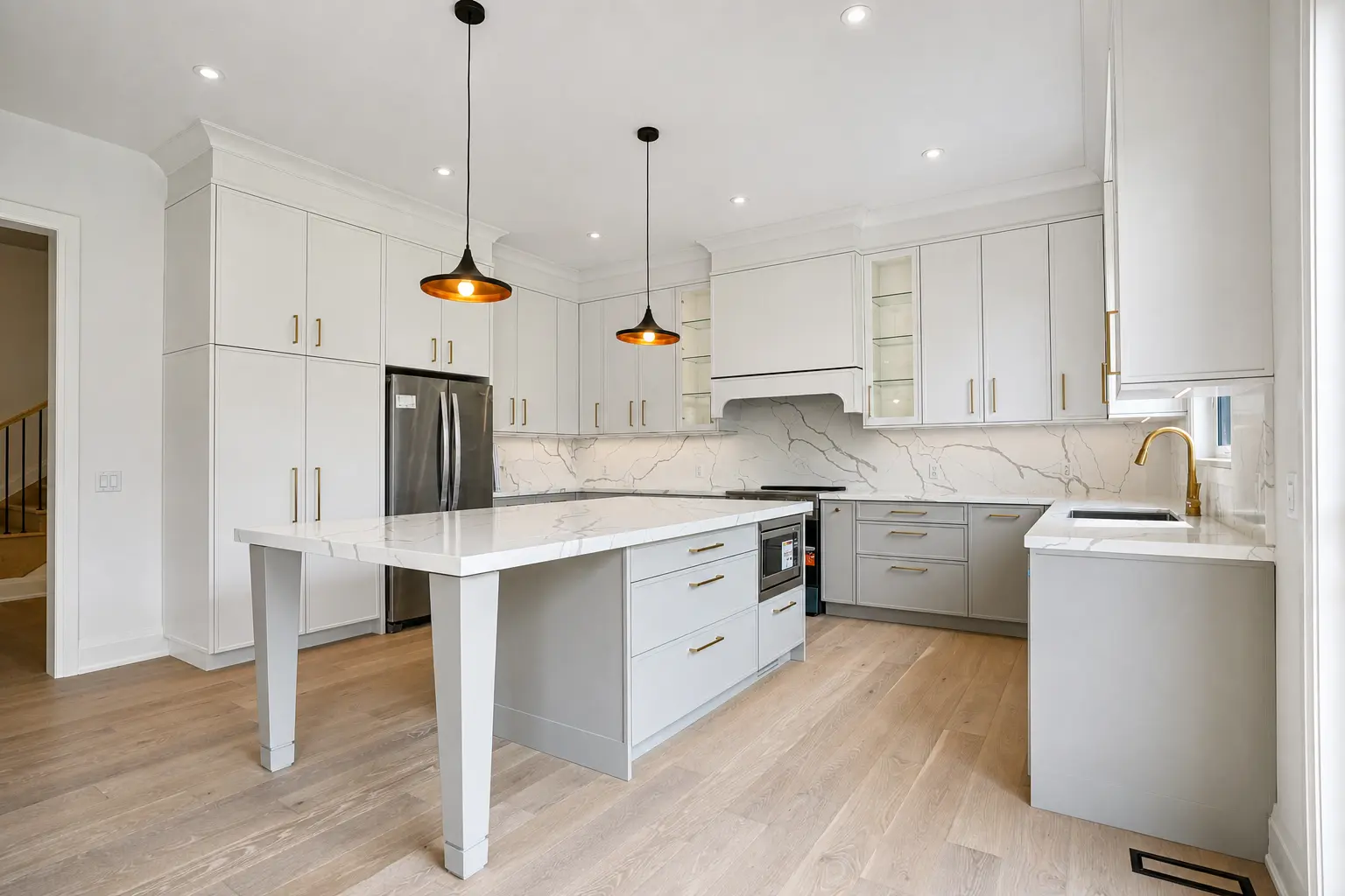 Kitchen with quartz island, marble backsplash and brass hardware