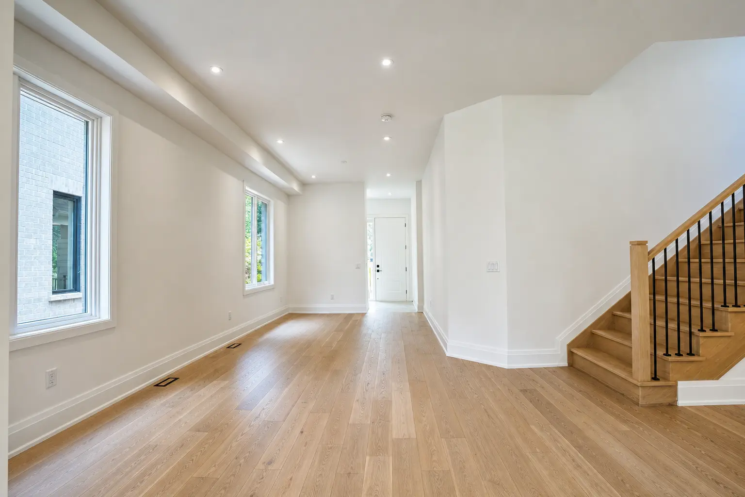 Open main floor with wide-plank oak floors and oak staircase