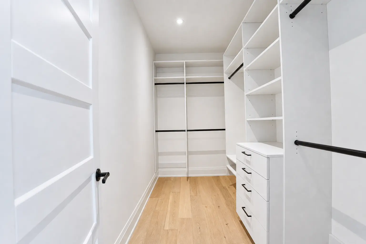 Walk-in closet with custom shelving, hanging rods and drawer bank