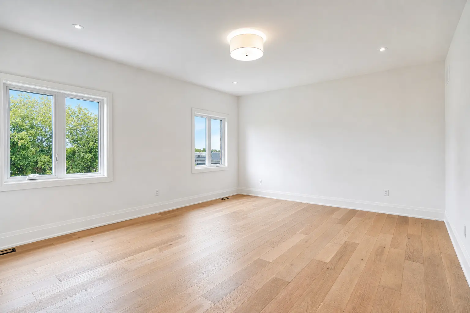 Bright bedroom with two windows and light oak flooring