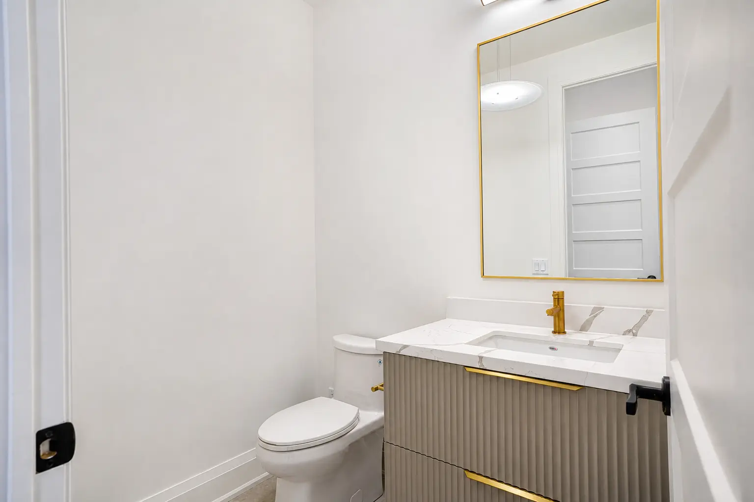 Powder room with fluted vanity, quartz top and brass fixtures