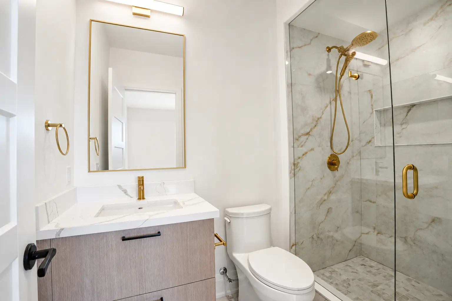Guest bath with marble glass shower, brass fixtures and floating vanity
